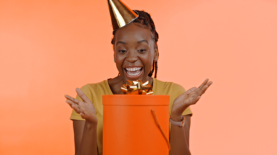 Birthday, surprise and black woman with present, box or gift in studio background or celebration. Wow, congratulations and excited winner of giveaway, package or product on offer for party and event