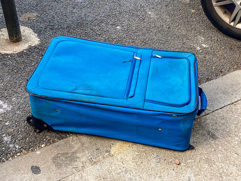 High angle view of an abandoned blue suitcase lying down on the street