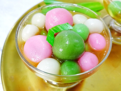 Wedang ronde is a warm drink made from ginger and colorful balls made from a mixture of sticky rice flour and rice flour filled with chopped peanuts and sugar. wedang ronde in glass bowl. close up.