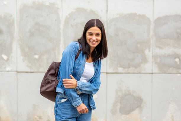 istock young woman smiling with bag by wall 1770684285