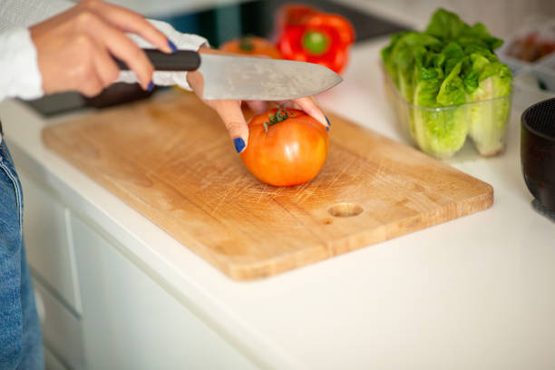 istock female hand cutting tomato with knife 1770684836