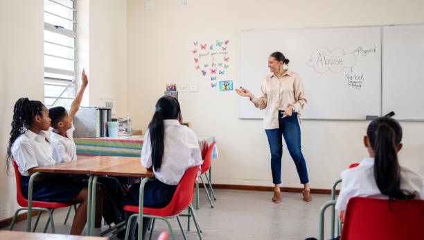 istock Boy raising hands to answer question during lesson in school classroom 1770684874