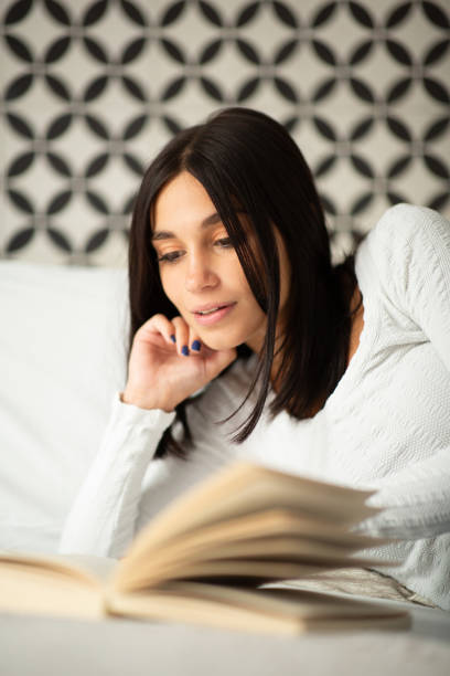 istock beautiful young woman relaxing in bed reading book 1770685414