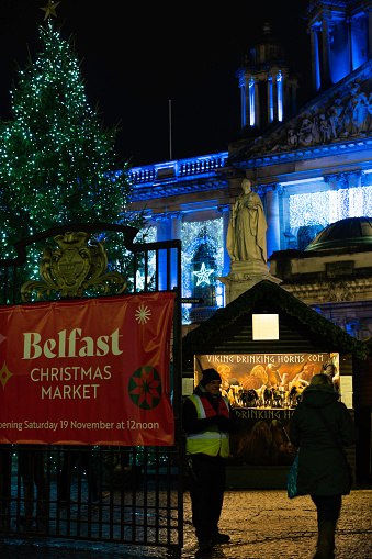 Belfast, Northern Ireland, UK - December 12, 2022: Tourists and locals alike visiting the Belfast Christmas Market illuminated at night during the holiday season.