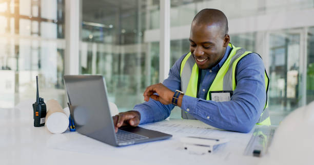 istock Laptop, time and a black man construction worker in an office for planning a building project. Computer, watch and a happy young engineer in the workplace for research as a maintenance contractor 1770711386