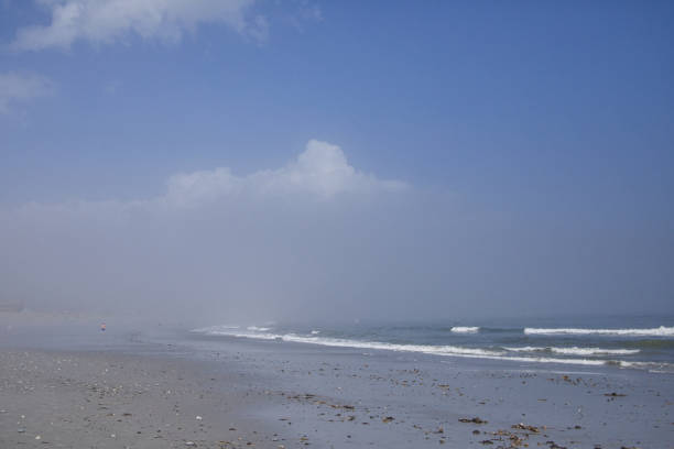 Scenes of ocean waves, ripples in the sand, mist in the air, blue sky with clouds