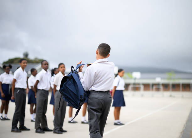 istock Back view schoolboy swings rucksack onto back lining up for first day back at school 1770718818