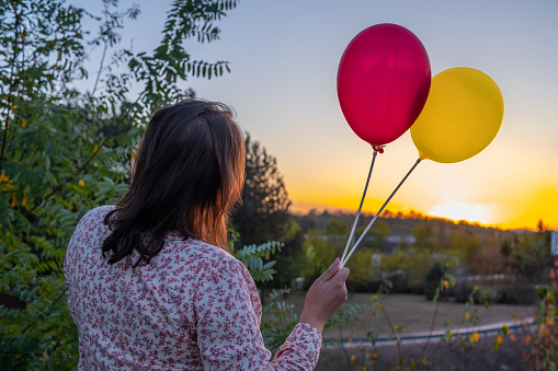 Young woman with two balloons spending time in the park.