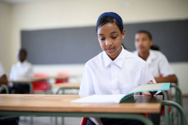 Front view girl opens schoolbook on desk in classroom