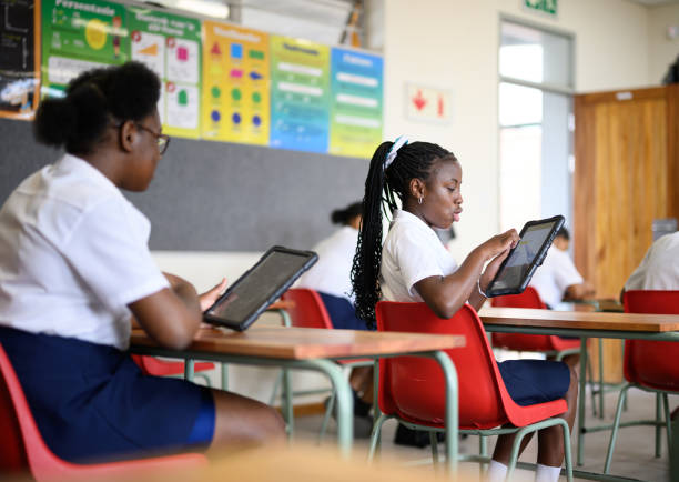 istock Girl looks over shoulder showing classmate equation on digital tablet screen 1770719946