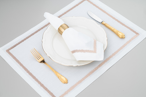 Flat lay empty folded linen napkin and golden cutlery isolated on white background. Fork and knife top view