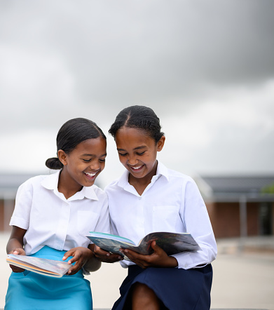 Schoolgirls in courtyard reading textbooks studying together