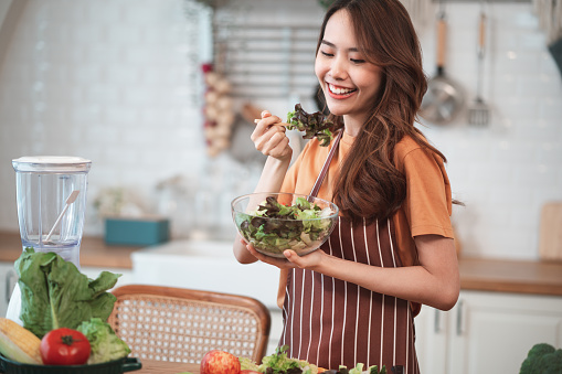 Young Asian woman is preparing a fresh healthy vegan salad with many vegetables in the kitchen, Dieting Concept. Healthy food Lifestyle. Cooking At Home.