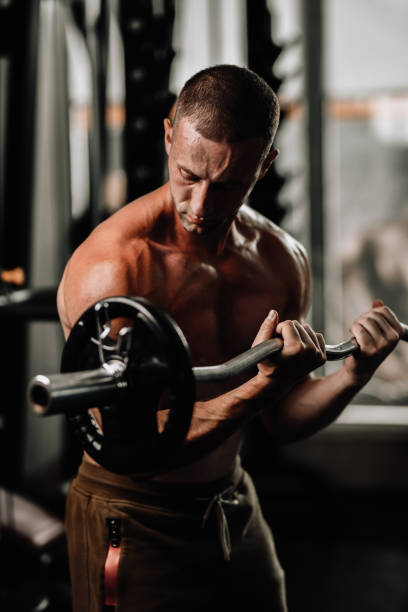 istock Athletic Male Using Barbell To Work On Biceps In Gym 1770753600