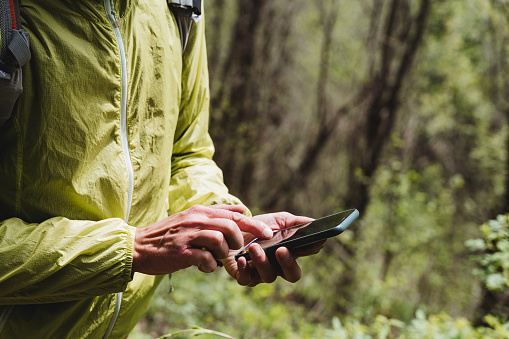 The phone lies in the hand of a person, typing with a finger on a smartphone, cellular communication in the forest, the use of gadgets on a hike. High quality photo