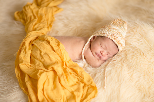 Newborn girl sleeping comfortably on a blanket and yellow background. Selective focus.