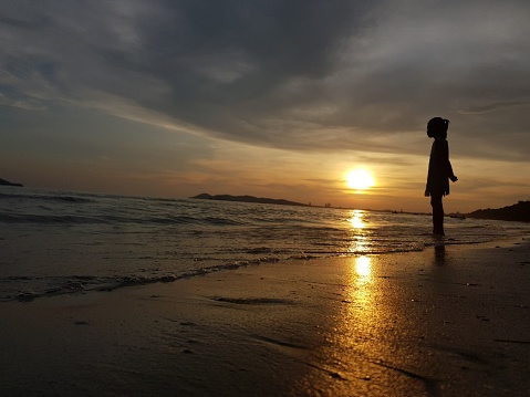 A little girl alone at beach before the sun go down.
