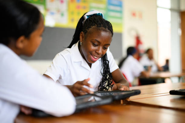 istock Young African schoolgirl working with classmate on digital tablet  in mathematics class 1770758803