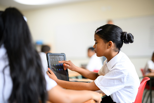 Young schoolchildren using digital tablets to learn maths in class