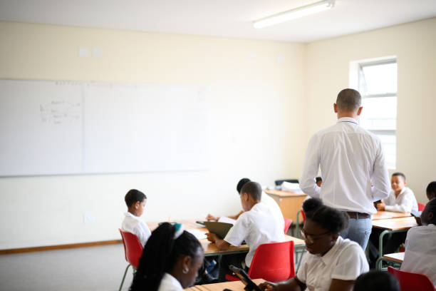 istock Background with copy space back view teacher in class with students working on digital tablets 1770759665