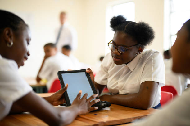 istock Close up over shoulder view black schoolgirls using digital tablet together in class 1770765001