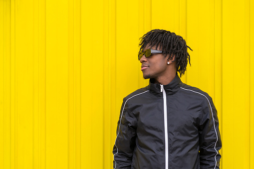 Portrait with copy space of an African cool young man with trendy clothes standing outdoors