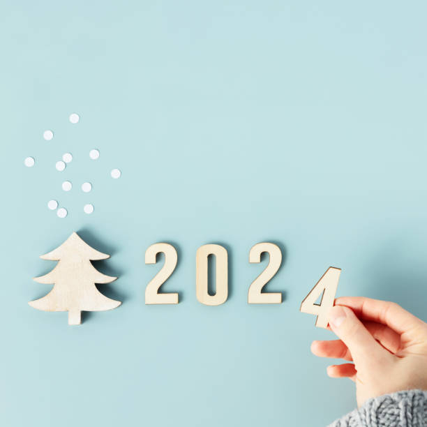 2024년 새해의 숫자로 나무 숫자를 접는 손의 이미지를 닫습니다 스톡 사진