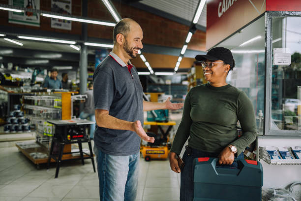 male manager of a hardware store helping a smiling customer - sales clerk store manual worker retail imagens e fotografias de stock