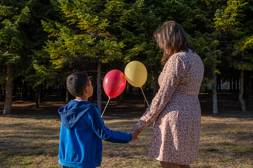 Young woman and child with two balloons spending time in the park.