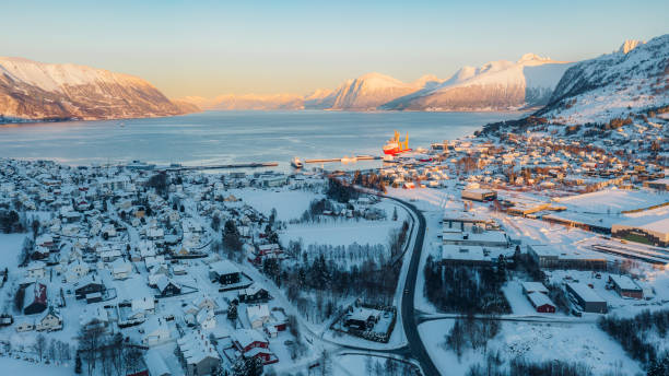 vista aérea do dramático pôr do sol de inverno sobre a cidade cênica por fiorde com carros dirigindo na estrada na noruega - more objects - fotografias e filmes do acervo