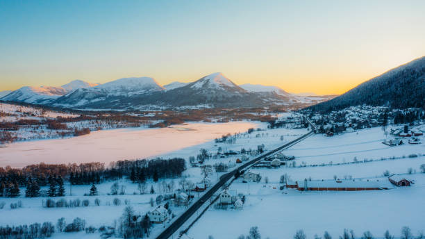 vista aérea do dramático pôr do sol de inverno sobre a cidade cênica pelo lago com carros dirigindo na estrada na noruega - more objects - fotografias e filmes do acervo