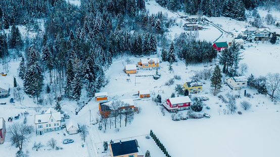 Drone panoramic photo of colourful buildings in Nordic style by the pine forest covered b deep snow in the city of Norway, Scandinavia