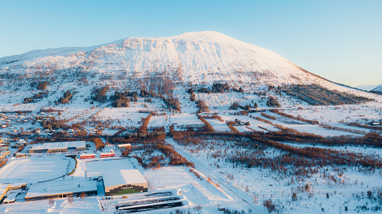Drone panoramic photo of the beautiful Nordic town in the mountains covered by fresh snow during idyllic colourful sunset in Scandinavia
