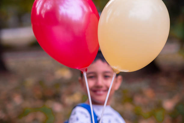 A child with two balloons spending time in the park.