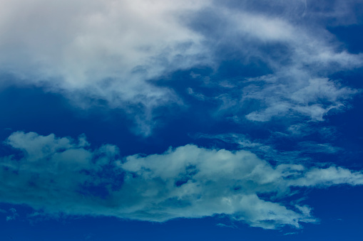 Beautiful sunrise clouds on a summer morning with pinks and blues. Cloudy cloud background and texture. Cluster of clouds with gloomy colors. Sunrise sky landscape travel serene tranquil view with multiple beautiful natural colors.