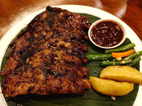 Close-up shot of BBQ pork ribs with fries and vegetables