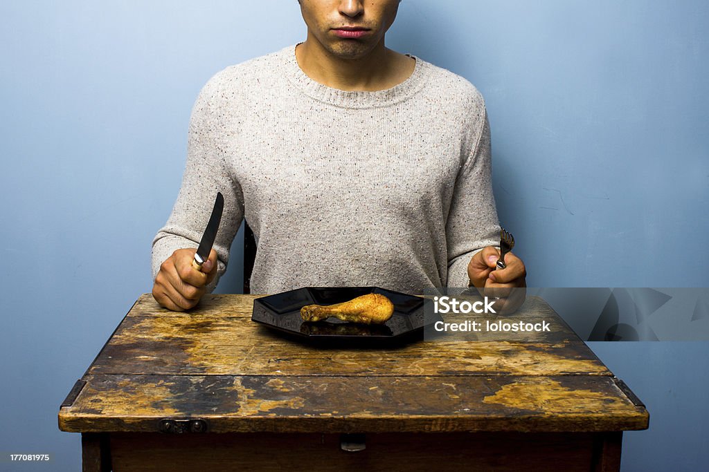 Young man having a chicken drumstick to eat Adult Stock Photo