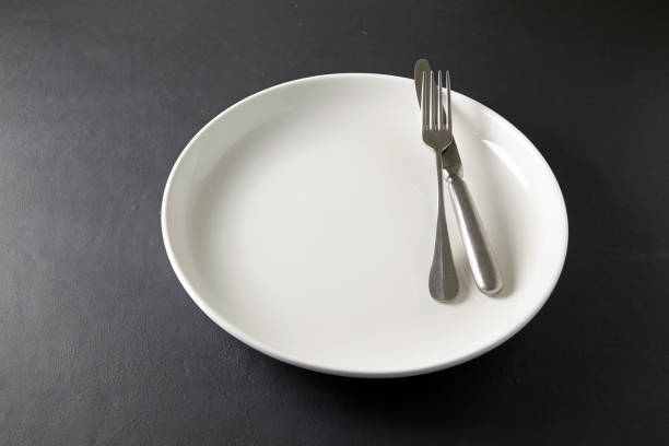 istock Empty white ceramic plate with cutlery on a black stone table. Template for displaying food on the menu 1770820807