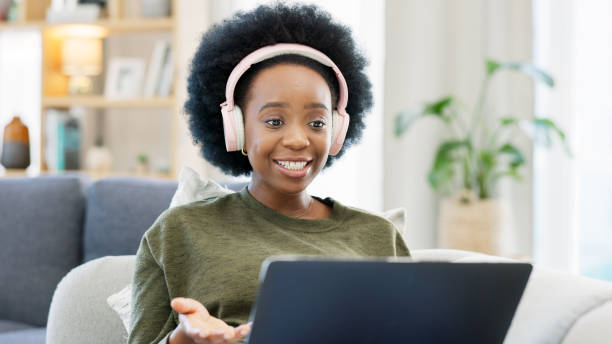 istock Woman, student and video call on laptop for home education, e learning and online course on sofa. Young african person on computer for virtual college, listening on headphones and studying on couch 1770847681
