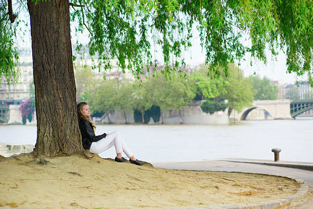 Girl reading under a tree near Seine