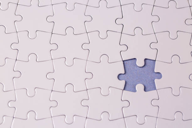 istock Missing jigsaw puzzle pieces. Business concept. Fragment of a folded white jigsaw puzzle and a pile of uncombed puzzle elements against 1770864160