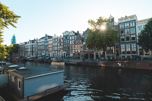 Sunset illuminates a water canal and adjacent buildings in the capital city of Amsterdam, the Netherlands. Venice of the North.