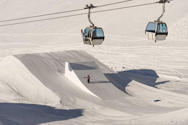 Snowpark Shaper shaping a kicker with a shapetool .Winter dolomites in Italy. Winter in Madonna di Campiglio village and a ski resort in Italy. Madonna di Madonna di Campiglio and ursus snowpark in Val Rendena dolomites trentino Italy. snowpark r dando forma a un kicker con una herramienta de forma . dolomitas invernales en italia. invierno en el pueblo de madonna di campiglio y en una estación de esquí en el noreste de italia. madonna di madonna di campiglio y parque de nieve ur