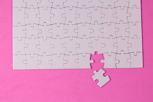 istock Missing jigsaw puzzle pieces. Business concept. Fragment of a folded white jigsaw puzzle and a pile of uncombed puzzle elements against 1770876806