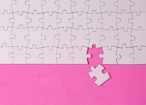 istock Missing jigsaw puzzle pieces. Business concept. Fragment of a folded white jigsaw puzzle and a pile of uncombed puzzle elements against 1770880208
