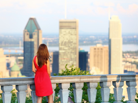 Montreal. xwoman looking at Montreal downtown skyline cityscape. Tourist girl in red dress on Mont Royal in spring or summer.