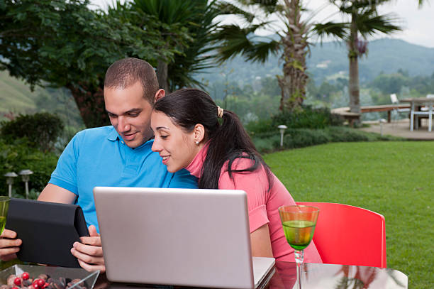 Young couple in terrace with computer and wireless tablet stock photo