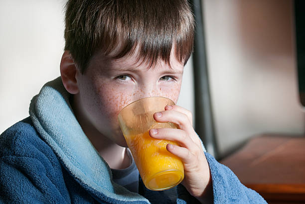 istock boy with orange juice at breakfast 177090042