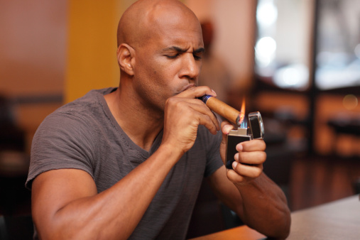 Image of a mature black male lighting his cigar