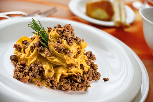 Dish with tagliatelle with wild boar sauce on a laid table